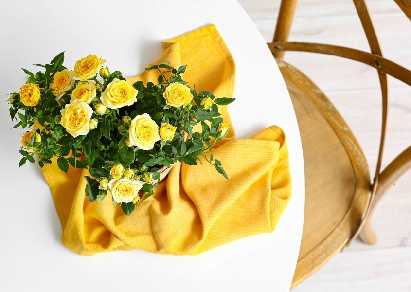yellow flowers and napkin on white round dining table