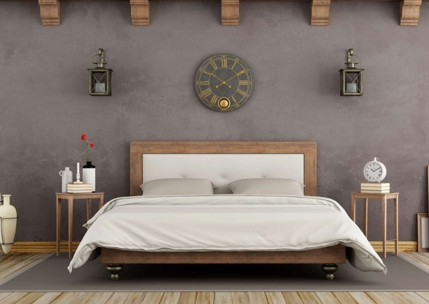 King size wooden bed frame with white covers against a grey wall with large circular clock