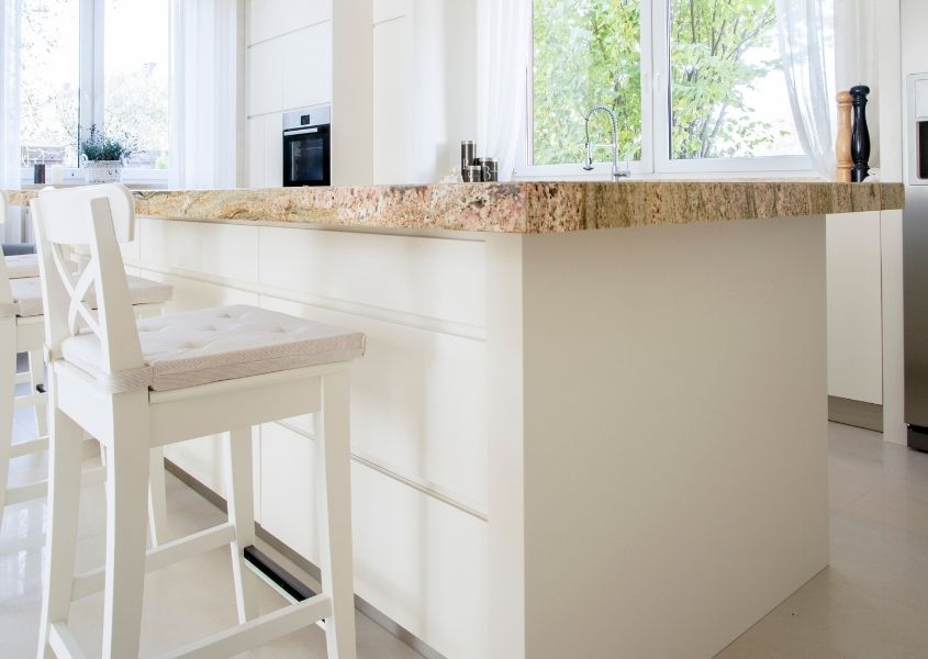 White wooden bar stool under white kitchen island with brown marble top