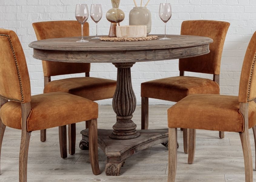 round reclaimed wood dining table with pedestal leg and orange velvet dining chairs