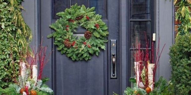 Large green Christmas wreath hanging on dark grey front door