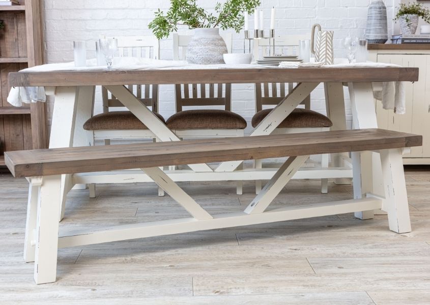 White painted reclaimed wood trestle dining table with matching wooden bench and three wooden dining chairs