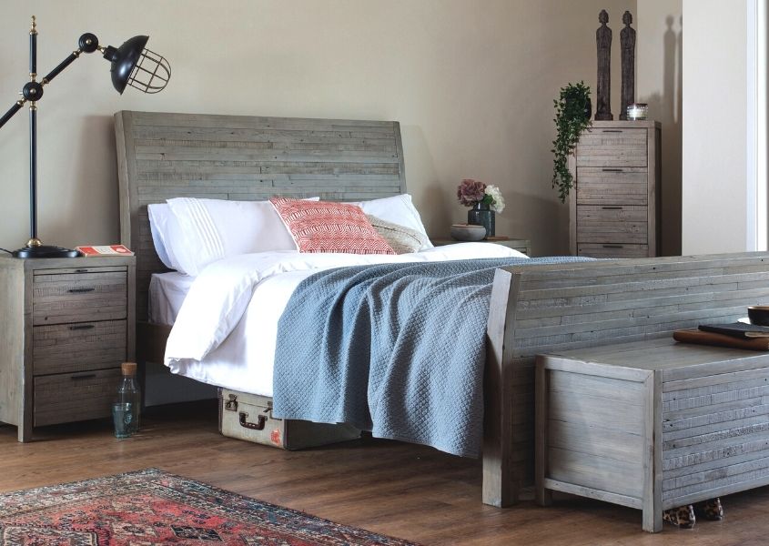 Grey reclaimed wood bed with matching wood blanket box and small bedside table with white covers and blue blanket
