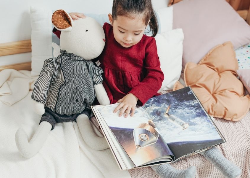 child reading book with cuddly toy for easy reading corner ideas your child will love blog