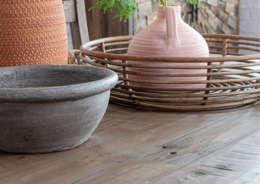 Close up of reclaimed wood dining table top with bamboo basket and stone pots