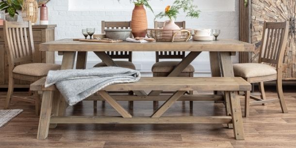 Reclaimed wood trestle dining table with wood bench and wooden dining chairs with blanket of bench