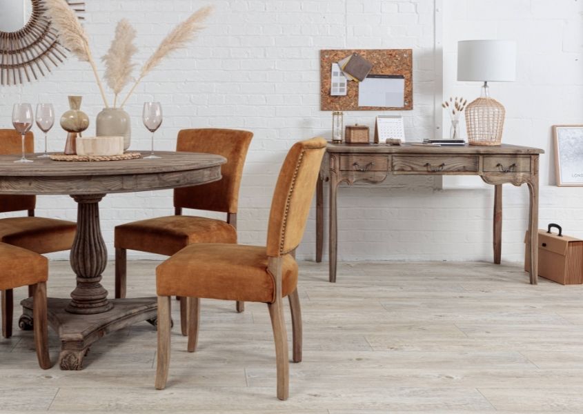 round dining table with orange velvet dining chairs and wooden writing desk in background