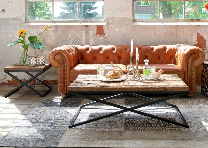Rustic coffee table in front of orange leather chesterfield sofa