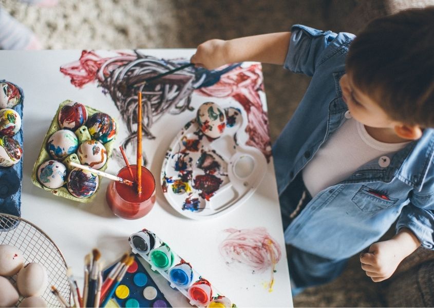 Young boy at a table painting eggs for Easter