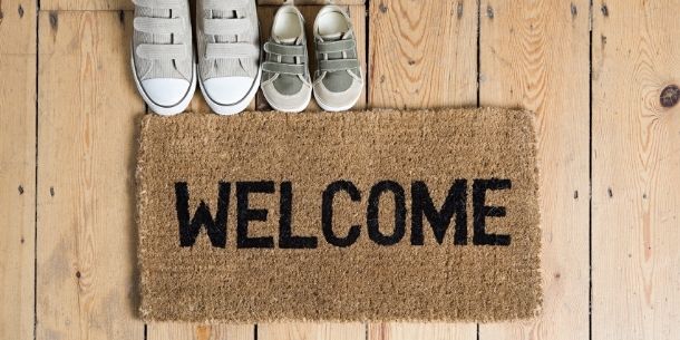 Hessian doormat with words welcome and two pairs of grey shoes