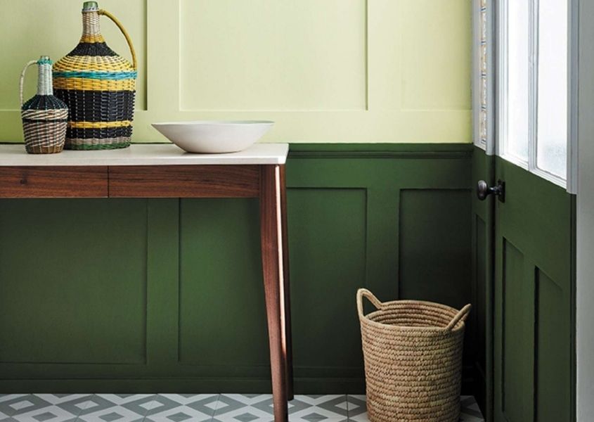 Wooden hallway console table with two tone painted wood panelling in dark green and light green with wicker basket on floor