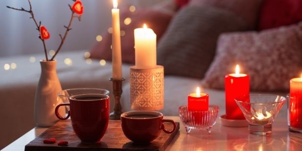 White and red candles lit on a coffee table with two red mugs