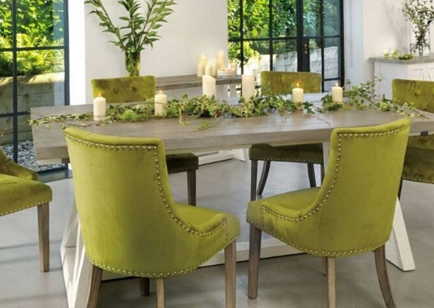 Green fabric dining chairs around a reclaimed wood dining table with ivy table decoration