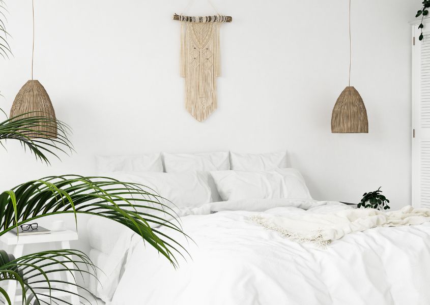 white bedroom with white bed, wall macrame and jute hanging pendant lights