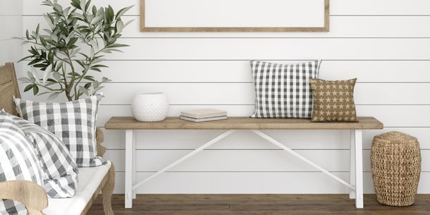 Rustic wooden bench with checked cushions and white painted panelled wall