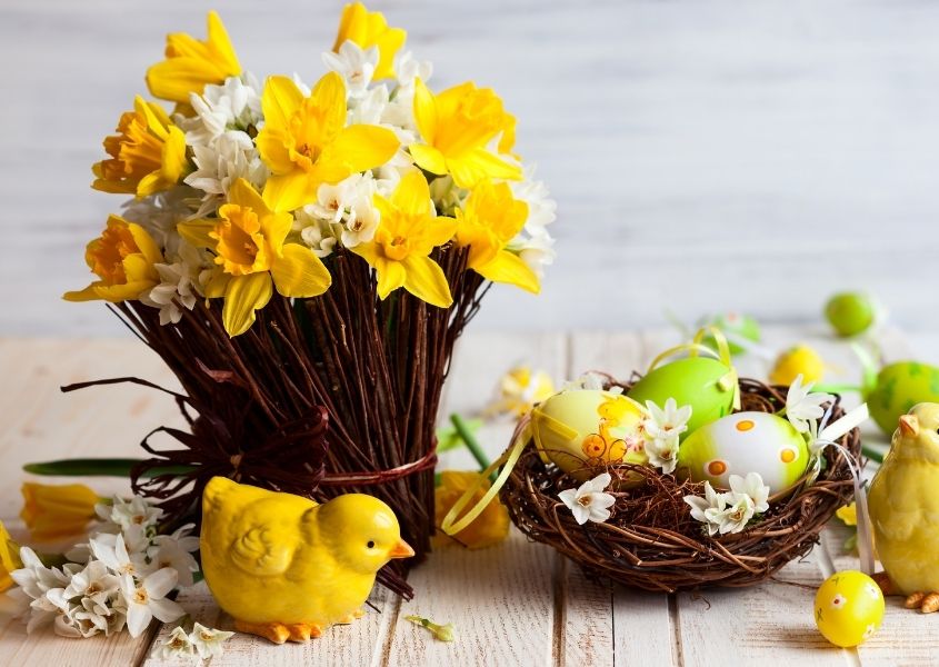 daffodils and nest of painted eggs on rustic dining table