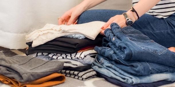 women folding a pile of clothes for how and where to store your summer clothes blog