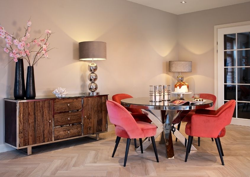 Dining room with round dining table and pink velvet dining chairs and reclaimed wood sideboard