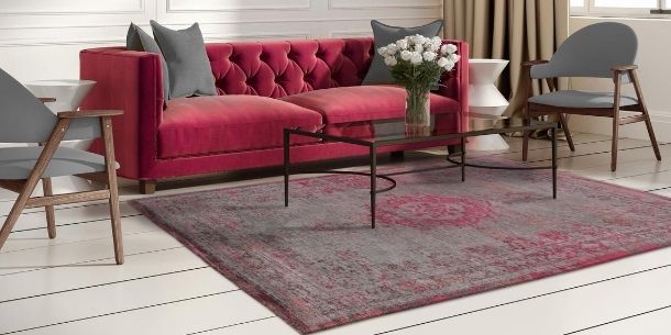 Pink velvet sofa with pink faded rug and metal and glass coffee table