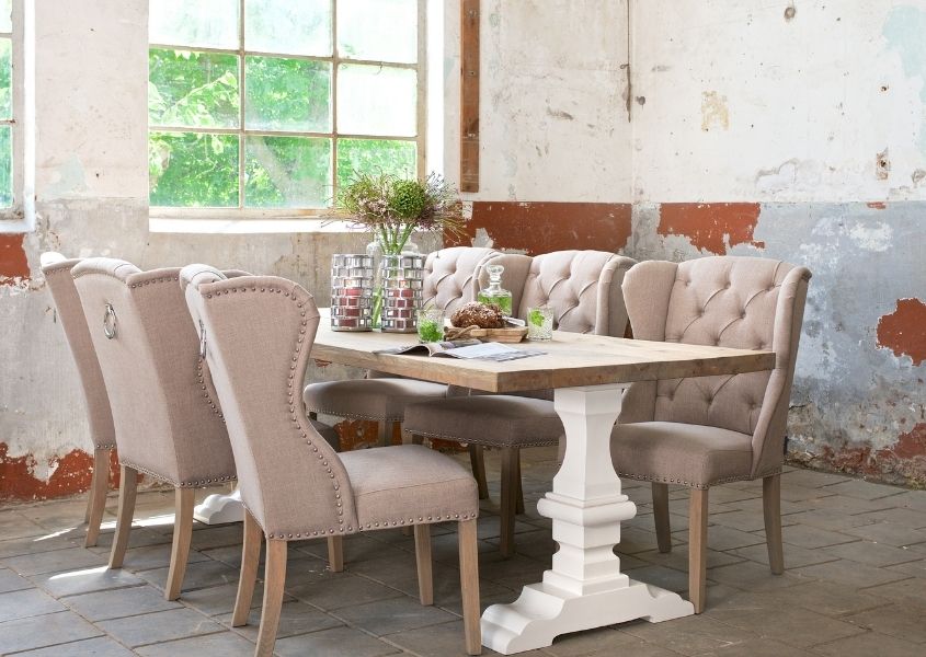 rustic wood dining table with white painted pedestal legs and cream fabric dining chairs