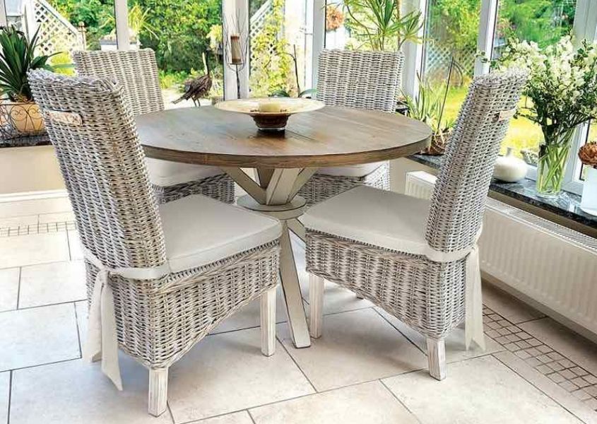 Grey rattan dining chairs and a round wooden dining table