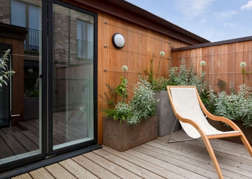 Decked outdoor patio with white deck chair and dark grey sliding patio door