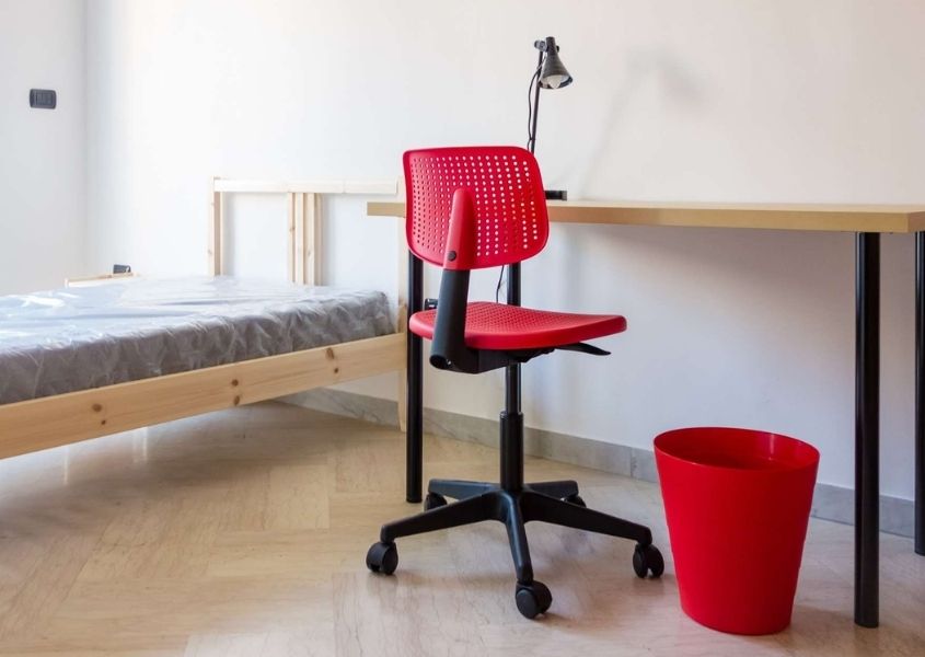 wooden single bed and white desk with red swivel office chair