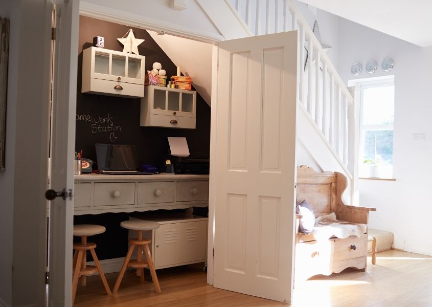 Home office in large cupboard under the stair with white painted wood doors