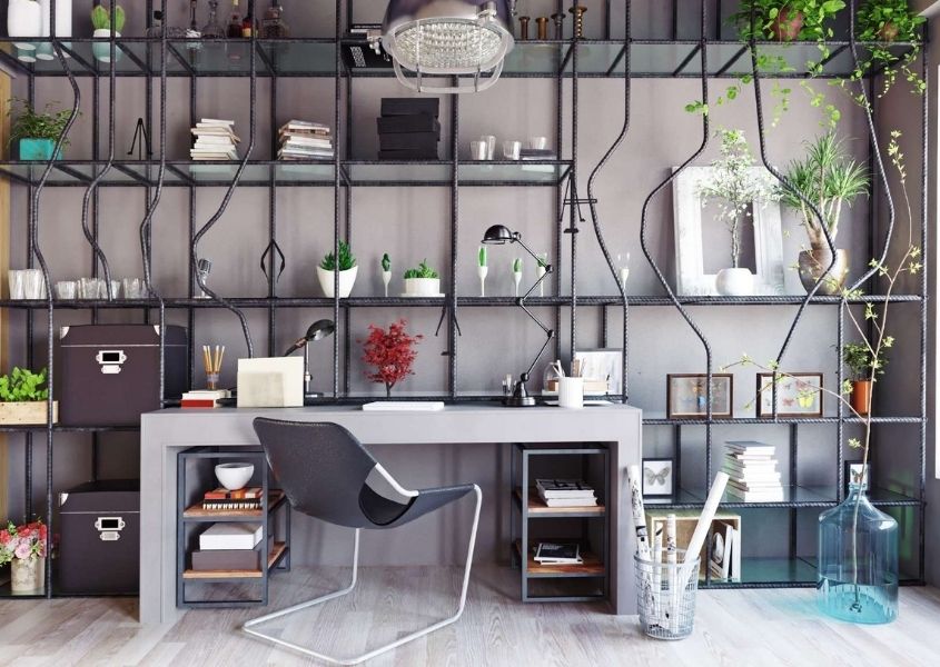 Concrete desk in front of a wall of metal pipe shelving filling entire wall with wires and hanging green plants