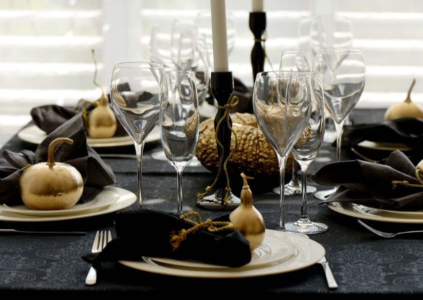 black table cloth on wooden dining table with gold painted pumpkins