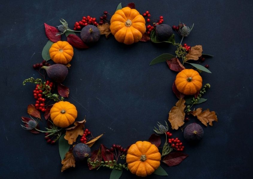 Halloween wreath with pumpkins and autumn flowers on dark blue background