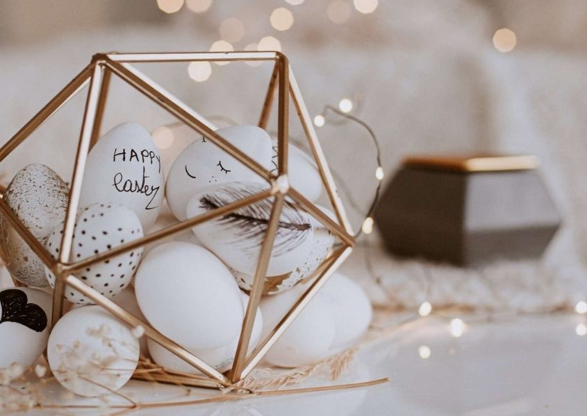 Close up of a collection white Easter eggs in gold framed geometric ornament as a table decoration