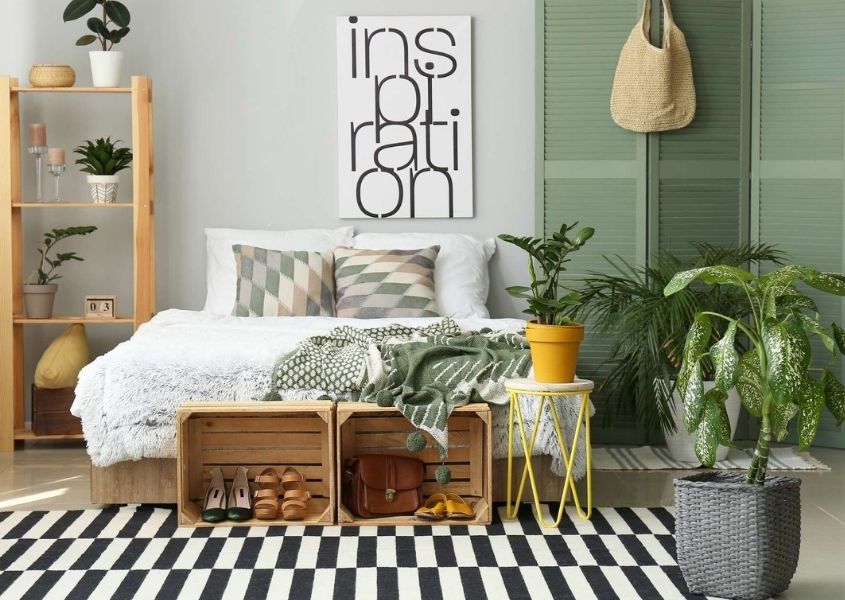 Contemporary bedroom with wooden palette boxes for shoe storage, black and white rug and green painted shutter screens behind bed