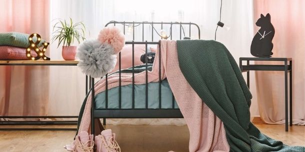 Industrial metal bed frame with industrial wooden bedside tables with pink and green covers and curtains