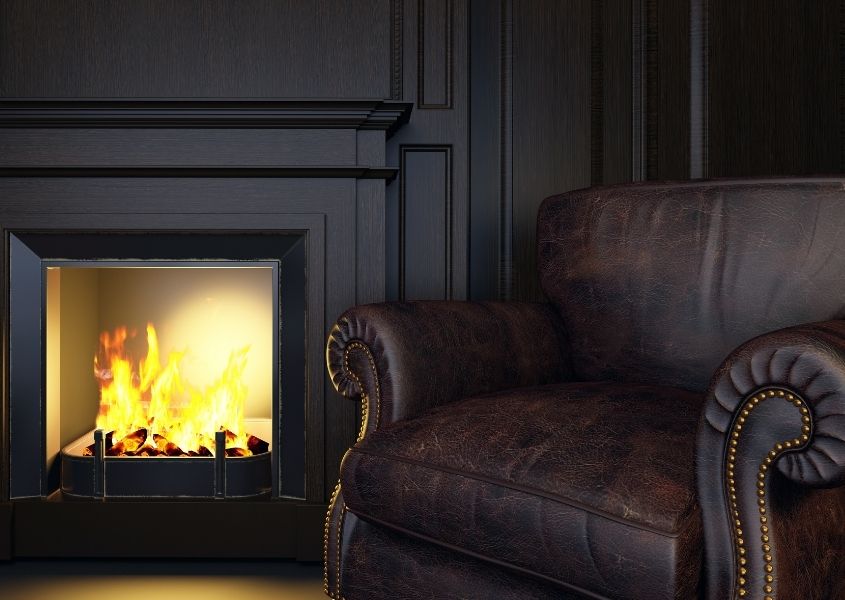 dark painted room with fireplace and dark brown leather chesterfield armchair