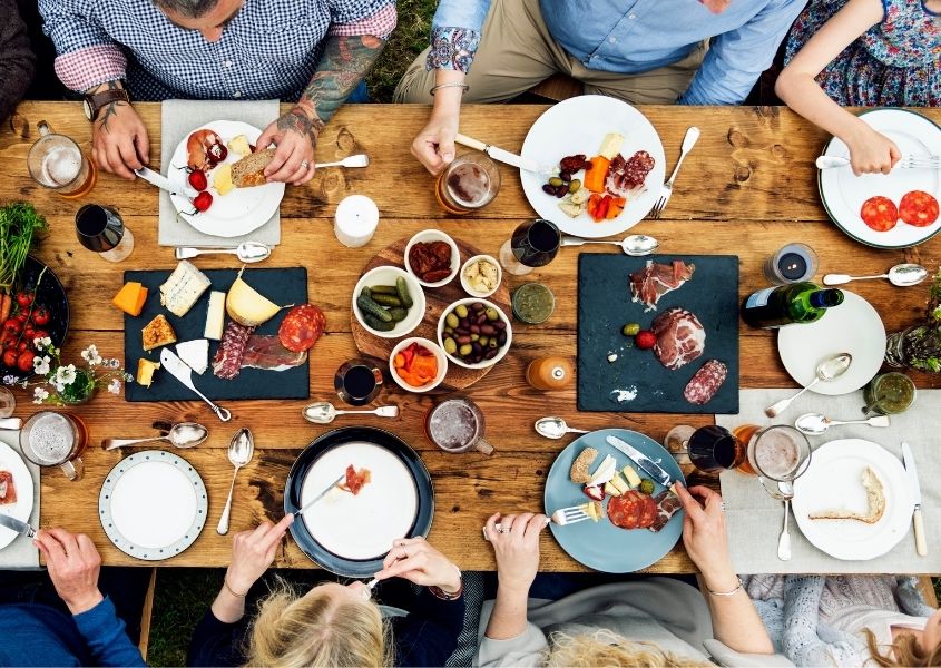 People sat around a large rustic dining table with food