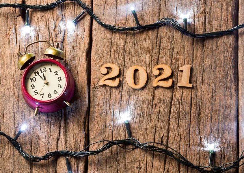 Alarm clock and wooden numbers spelling 2021 against rustic wood background