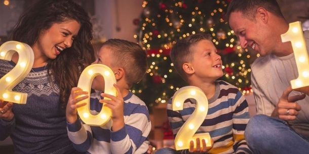 Family of four sat on a sofa each holding a 2021 number