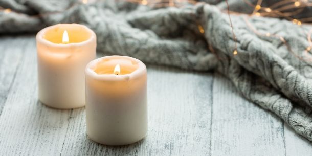Two candles on a rustic wood table with a wool blanket