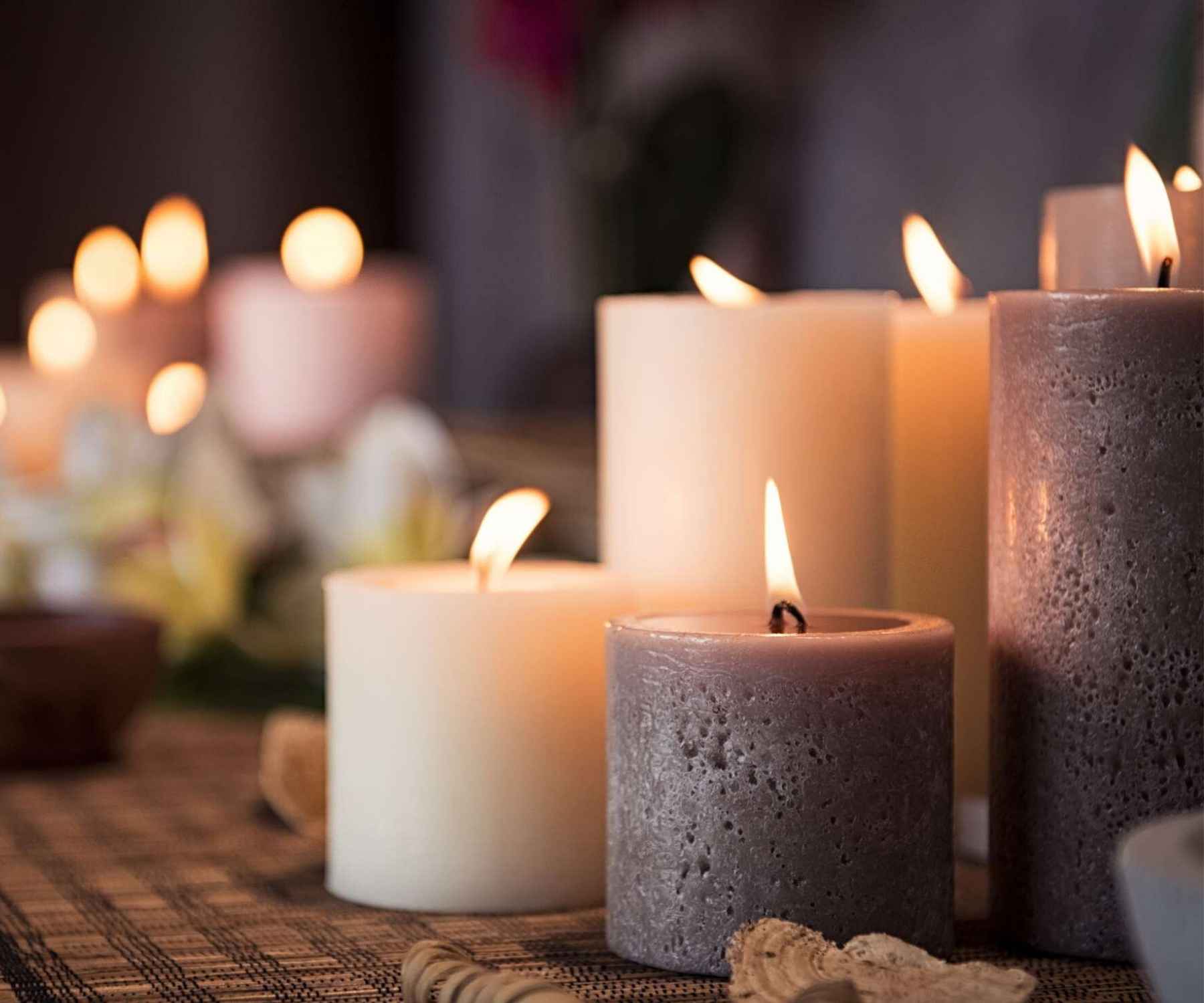 Close up of three lit candles on a wooden table