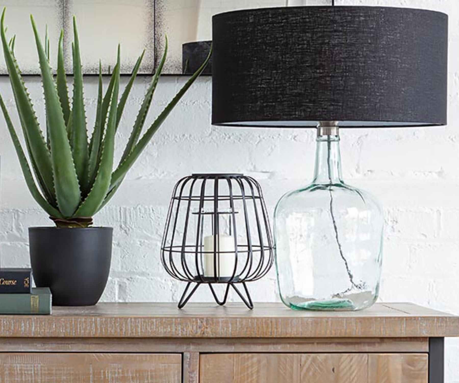 Glass table lamp on wooden sideboard with aloe vera plant