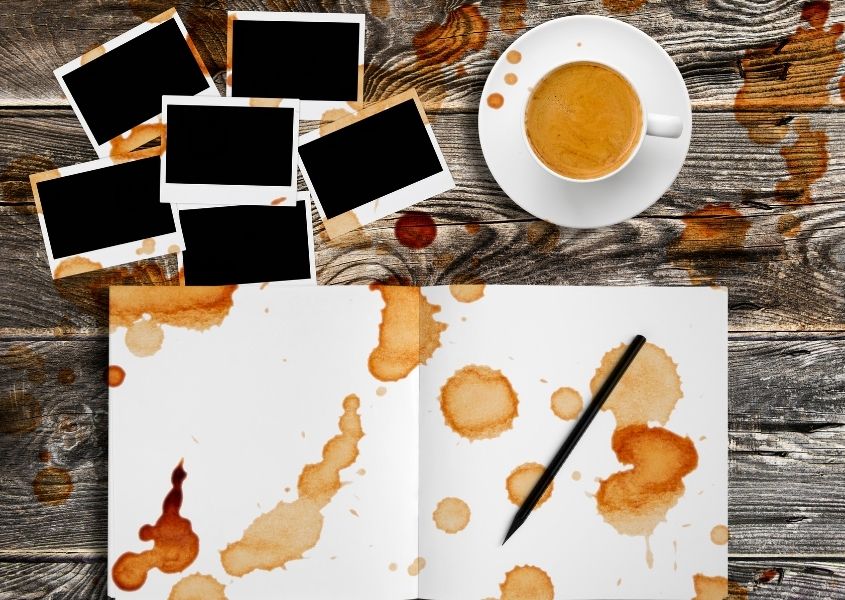 Rustic wood with white note paper covered in coffee splashes all over and cup of coffee