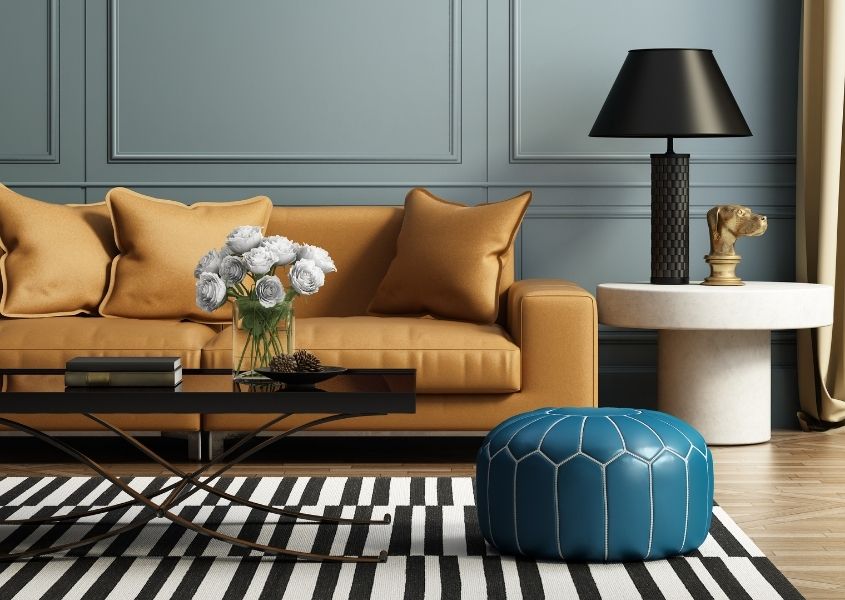 mustard fabric sofa with black and white rug and blue leather footstool
