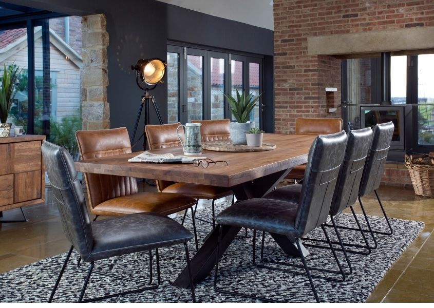 Large reclaimed wood dining table with grey faux leather chairs in industrial style dining room