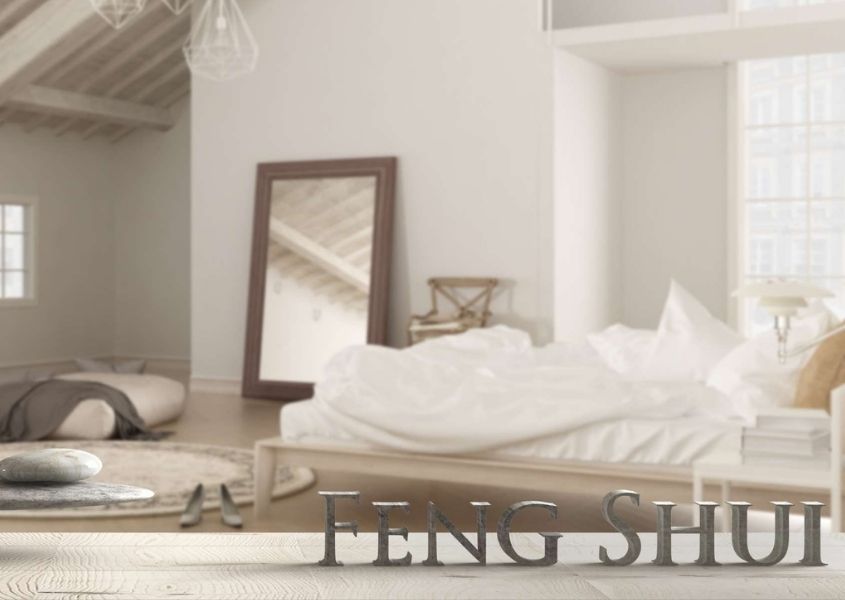 Bedroom with white bed and large floor mirror with words feng shui