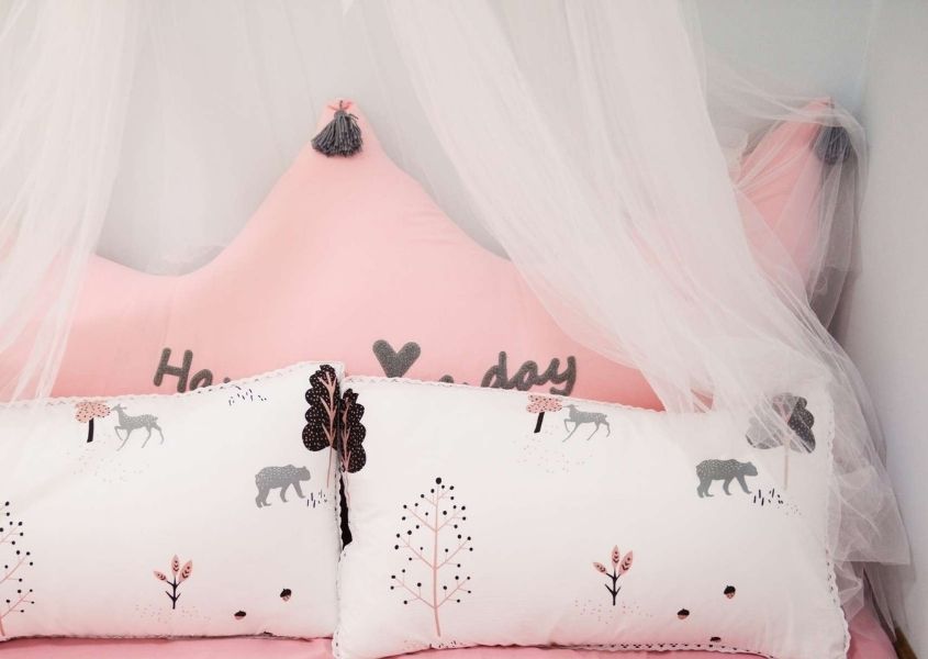 Pink child's bed with sheer fabric draped above