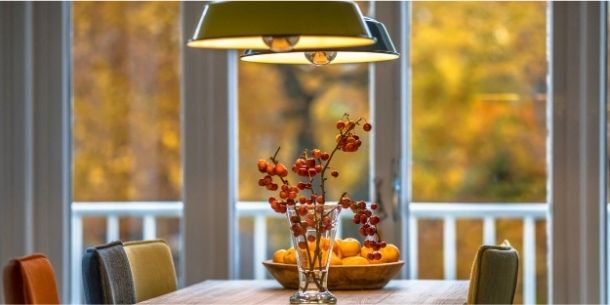 Green hanging lights over wooden table with red berries