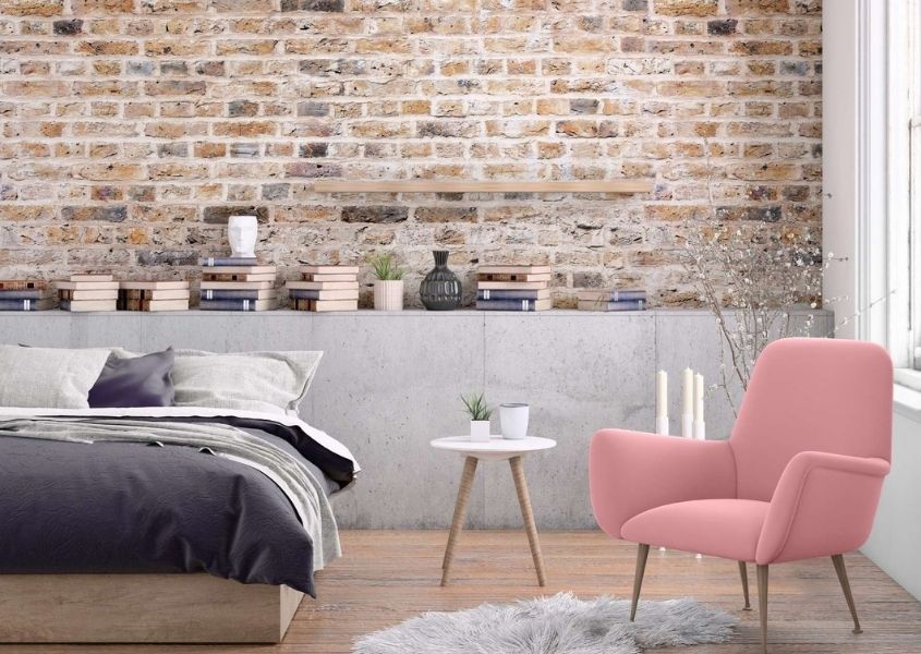 industrial bedroom with exposed brick wall and pink armchair