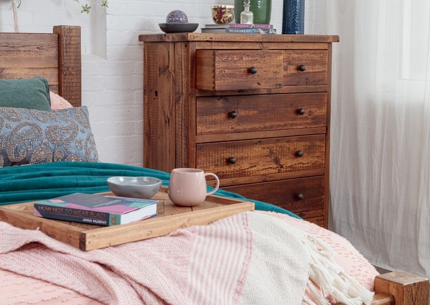 wooden chest of drawers with wooden bed and pink covers