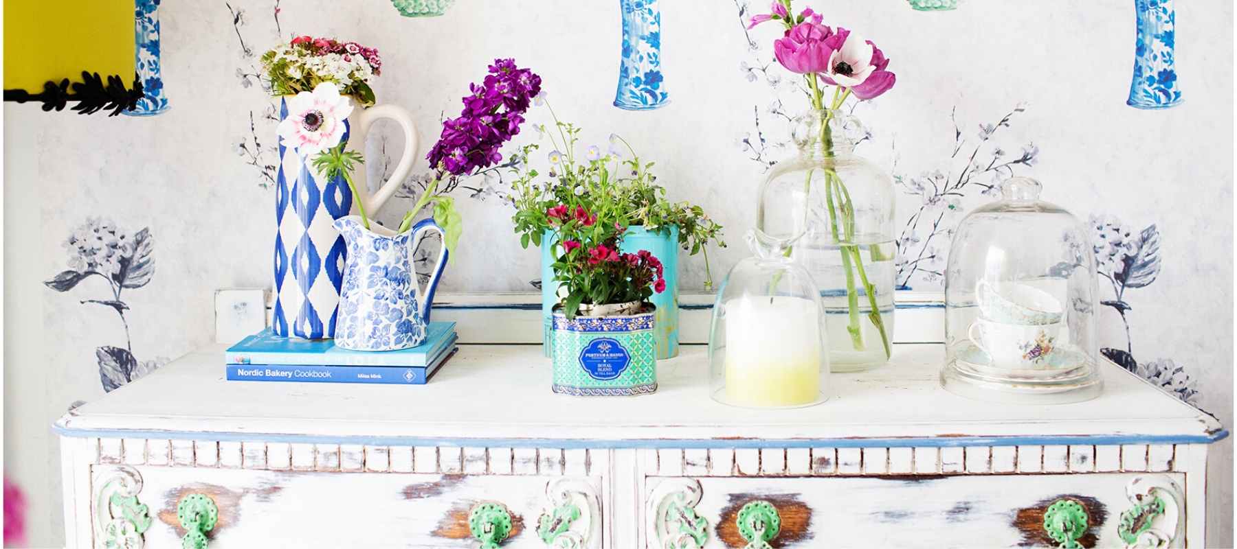Colourful pots and vases with flowers on white dressing table